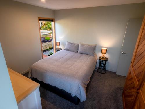 um quarto com uma cama com 2 candeeiros e uma janela em Roydons - Kaiteriteri Upstairs Holiday Unit em Kaiteriteri