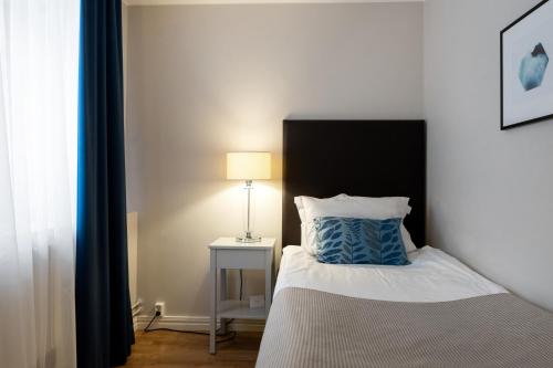 a bedroom with a bed with a blue pillow and a lamp at Elite Grand Hotel Norrköping in Norrköping