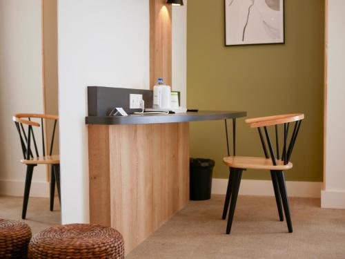 a reception counter with two chairs and a table at Best Western Le Bois de la Marche in Poitiers
