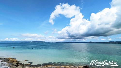 a view of the ocean with people in the water at 【KouriGarden】古宇利島の海と緑と星を眺める一棟貸切別荘ヴィラ in Nakijin