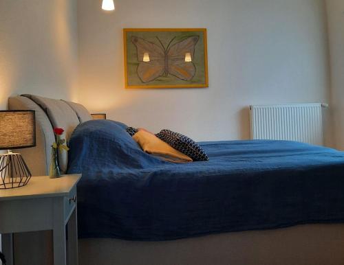 a bedroom with a blue bed with a butterfly picture on the wall at Ferienwohnung Altstadthaus in Oberkirch