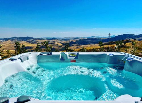 a jacuzzi tub with a view of the mountains at MonteSoprano Agriturismo - Resort - Spa - Gym -Camping - Suite in Capizzi