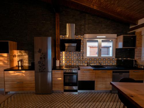 a kitchen with wooden cabinets and a stainless steel refrigerator at Casa Rural La Molina 4* in Navamorcuende