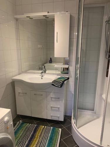 a white bathroom with a sink and a shower at Bo i hjertet av Sunnmøre in Ålesund