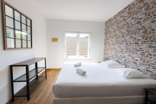 1 dormitorio con cama y pared de ladrillo en Studio Elément - Feu, en Saint-Aignan