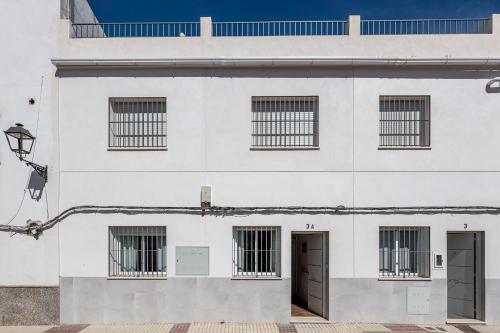 un edificio blanco con dos puertas y ventanas en Algaba aral en Alcalá del Río