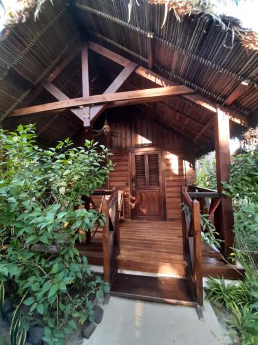 a wooden pathway leading to a cabin with a thatched roof at Le Moya Beach in Nosy Be