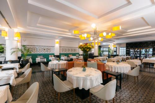 a restaurant with white tables and chairs and flowers at Castanheiro Boutique Hotel in Funchal