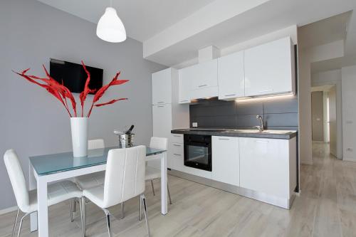 a kitchen with white cabinets and a blue table and chairs at Residence Armony in Misano Adriatico