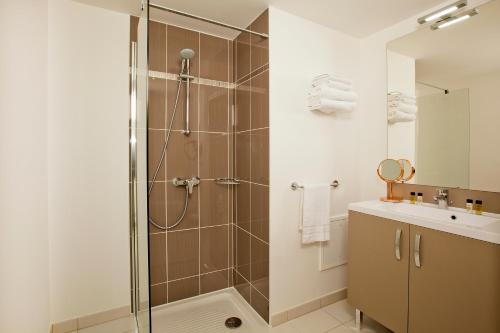La salle de bains est pourvue d'une douche et d'un lavabo. dans l'établissement Residhome Asnieres Park, à Asnières-sur-Seine