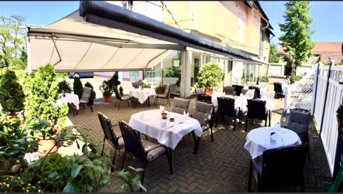 ノイエンビュルク・アム・ラインにあるHotel Kroneのテーブルと椅子、白い傘が備わるレストラン
