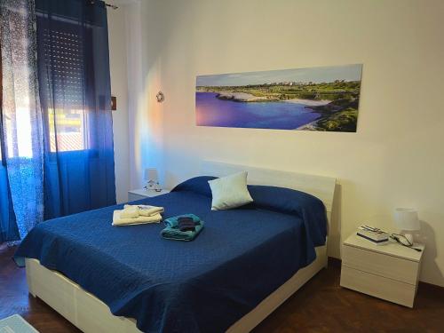 1 dormitorio con 1 cama con sábanas azules y una pintura en Casa Clelia, en Porto Torres