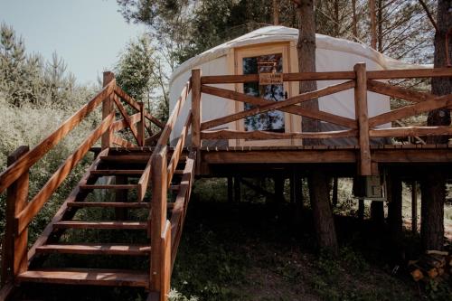 a tree house with stairs leading up to it at Jurty z widokiem, prywatna balia- DZIKOLAS GLAMPING in Krasnobród