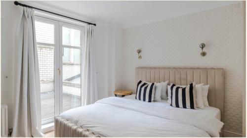 a white bedroom with a large bed and a window at Maddox House in London