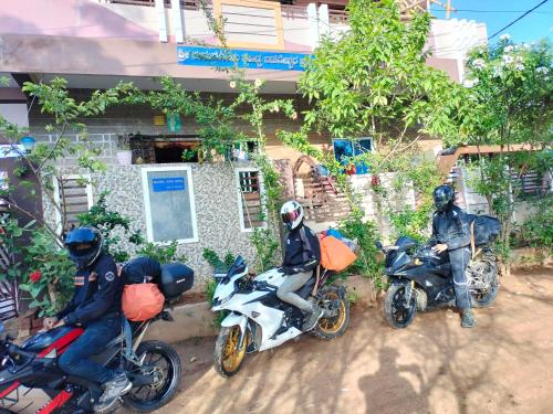 three people on motorcycles parked in front of a building at Prajwal home stay in Hampi