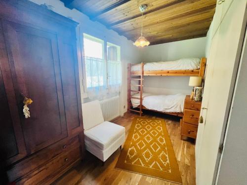 a room with a bunk bed and a chair and a door at Cosy Lodge in Madonna di Campiglio