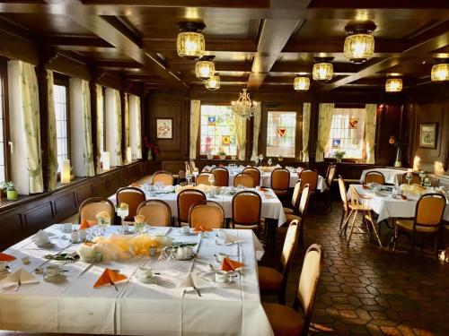une salle à manger avec des tables et des chaises blanches dans l'établissement Hotel Krone, à Neuenburg am Rhein