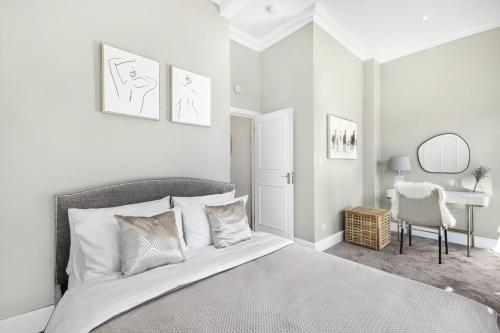 - une chambre blanche avec un lit et un bureau dans l'établissement Lovely large 1 bed renovated flat w balcony & 600MB WiFi, à Londres