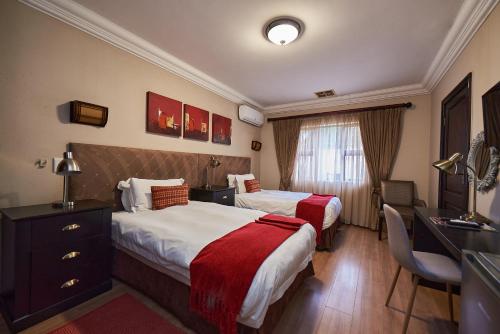 a hotel room with two beds and a desk at Ebandla Hotel & Conference Centre in Ballito