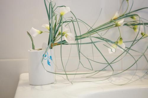 a white vase with flowers in it on a table at Gold n Blu Petalidi in Petalidhion