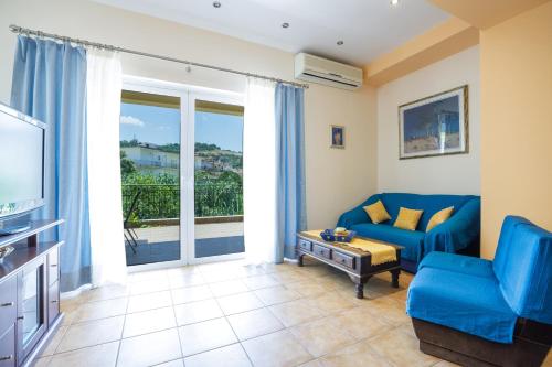 sala de estar con sofá azul y TV en Gold n Blu Petalidi en Petalidhion