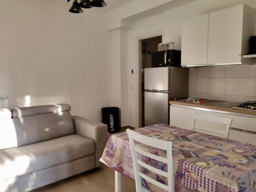 Tiny Green apartament in Rome - Magliana في روما: غرفة معيشة مع أريكة وطاولة ومطبخ