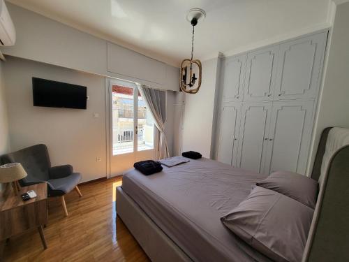 een slaapkamer met een bed, een stoel en een televisie bij Maria's Maisonette in Athene