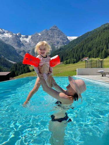 a woman holding a little girl in a swimming pool at Hotel Bella Vista in Trafoi