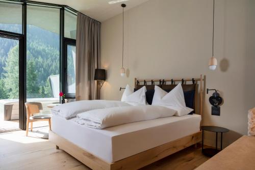 a bedroom with a large white bed and a large window at Olympic SPA Hotel - Adults Only in Vigo di Fassa
