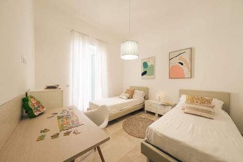 a white room with two beds and a table at HelloApulia - La Terrazza di Don Nino in Polignano a Mare