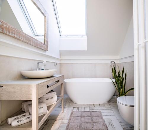 a bathroom with a tub and a sink and a skylight at Aqua Your Stay in Sasino