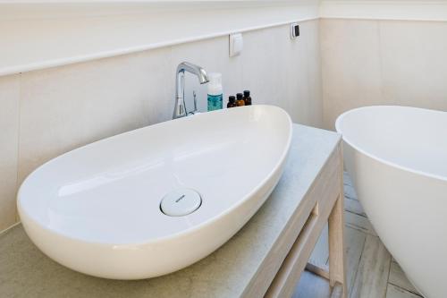 a bathroom with a white sink and a tub at Aqua Your Stay in Sasino