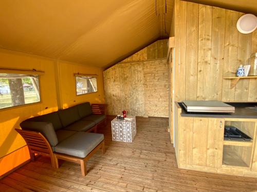 a living room with a couch and a table at Camping la Kahute - Tente lodge au coeur de la forêt in Carcans