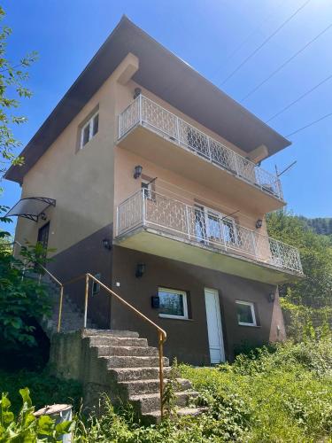 a house with stairs and a balcony on it at Apartment SunLight in Visoko