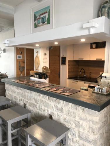 - une cuisine avec un comptoir en pierre et 2 tables dans l'établissement Villa Pigouille, à Sainte-Marie de Ré
