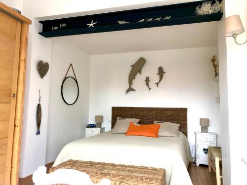a bedroom with a bed with an orange pillow and bats on the wall at Villa Pigouille in Sainte-Marie-de-Ré