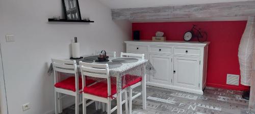 una cucina con tavolo, sedie e parete rossa di Appartement studio avec terrasse privatisée a Marmande