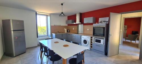 uma cozinha com uma mesa e uma cozinha com paredes vermelhas em Joli gîte chez Paulette à 10 min du Puy du Fou em Sevremont