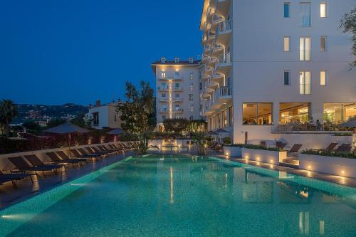 uma piscina em frente aos edifícios à noite em Hotel Conca Park em Sorrento