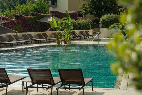 una persona che nuota in una piscina con sedie di Hotel Conca Park a Sorrento