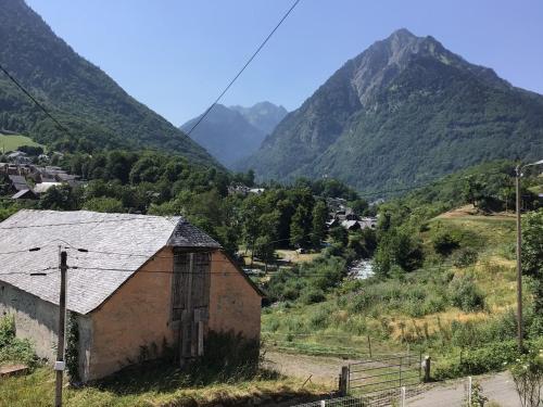 un antiguo edificio en un valle con montañas en el fondo en Villa Eth Mayouret en Cauterets