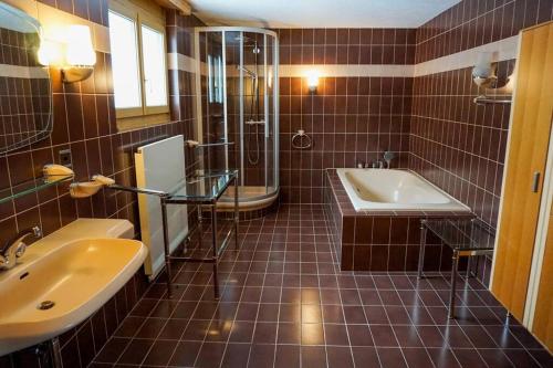 y baño de azulejos marrones con lavabo y ducha. en Grosse 2 ZImmer Wohnung mit Terrasse en Bad Ragaz