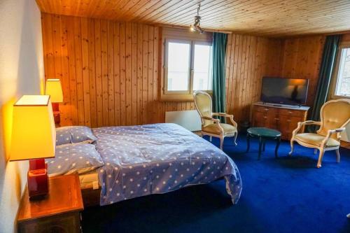 ein Schlafzimmer mit einem Bett und Stühlen sowie einem TV in der Unterkunft Grosse 2 ZImmer Wohnung mit Terrasse in Bad Ragaz