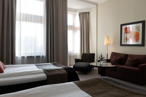 a hotel room with a bed and a couch at Elite Stadshotellet Luleå in Luleå