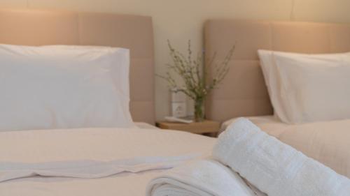 a bed with white sheets and pillows and a vase at l'olivier house in Kalabaka