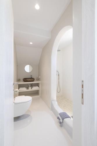 a white bathroom with a toilet and a sink at Studio 28 in Naxos Chora