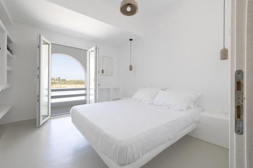 a white bedroom with a large bed and a window at Studio 28 in Naxos Chora