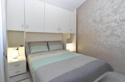 een kleine slaapkamer met een bed en witte kasten bij House Peroj 2195 in Peroj