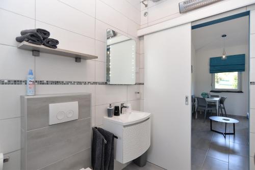 uma casa de banho branca com um lavatório e um espelho em House Peroj 2195 em Peroj