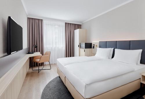 a hotel room with a large bed and a tv at Crowne Plaza Hamburg-City Alster by IHG in Hamburg